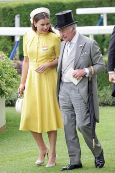 a man in a suit and tie standing next to a woman wearing a yellow dress