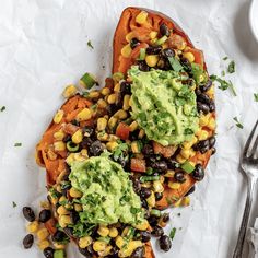 two sweet potatoes topped with guacamole and black beans