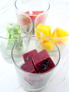 four glasses filled with different types of fruit and ice cubes on top of a table