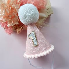 A sparkly little accessory to celebrate a big occasion! Perfect for Cake Smash photoshoots or that special touch to a 1st Birthday outfit, costumes and dress ups.  DETAILS ♕  1 x Party Hat lined with felt. Finished with mini pom trim, number of choice and fur Pom.  (any number available, not just for 1st Birthdays. Please select number) Elastic comes attached to wear around back of head. ♕ Matching "One" cake topper to go with handmade hat available. Select this option in the drop down to upgrad One Cake Topper, Mini Pom, Glitter Shadow, Hat Cake, Hat Party, Birthday Party Hats, 1st Birthday Outfits, 1st Birthdays, Wonderland Party