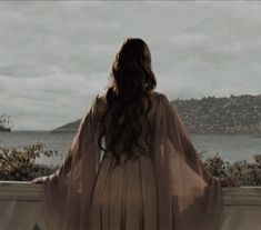 a woman standing on top of a balcony next to the ocean