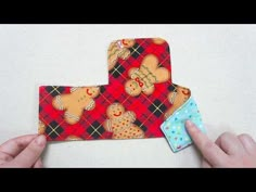 two hands are holding fabric pieces with gingerbreads on them, one is folded in the shape of a house