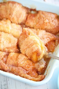 peach dumplings in a casserole dish with a spoon