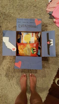 someone's feet are standing in front of an open box that has food inside