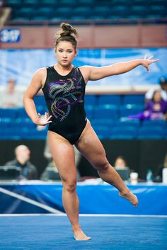 a woman in a black leotard is on a blue floor with her arms out