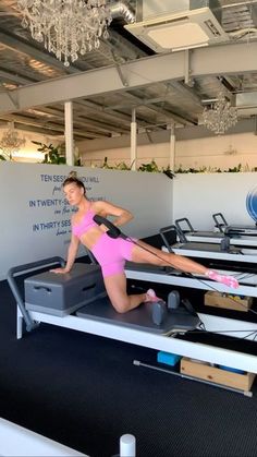 a woman in pink shirt and shorts doing pivots on an exercise equipment machine