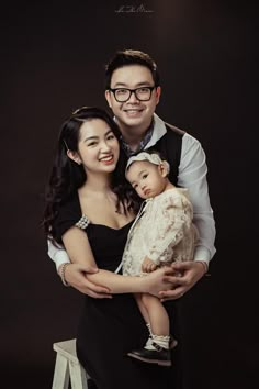 a man and woman holding a baby in front of a black background with the caption's name on it