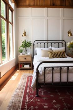 a bedroom with a bed, nightstand and two windows in it's center area