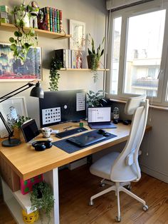 a desk with two computers on it in front of a large window and bookshelves