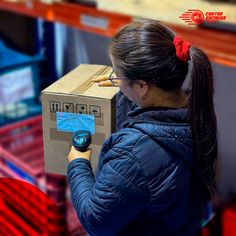 a woman in a blue jacket is holding a box