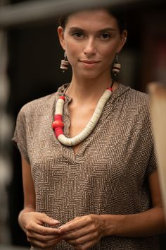 a woman standing in front of a bookshelf wearing a necklace with beads on it