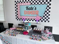 a table topped with cakes and cupcakes next to a sign that says kate's diner