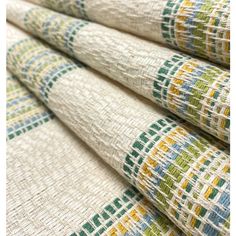 a close up view of a multicolored pattern on white fabric with green, yellow and blue stripes