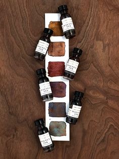 five bottles of ink sitting on top of a wooden table next to each other with different types of ink in them