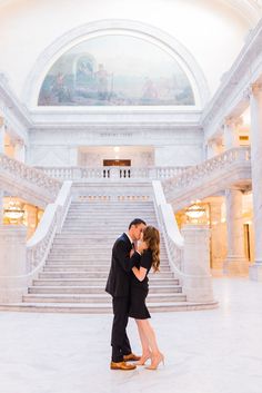 a man and woman kissing in front of some stairs