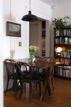 a dining room table and chairs with bookshelves in the background on a hard wood floor