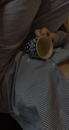 a person laying in bed with a cup on their lap