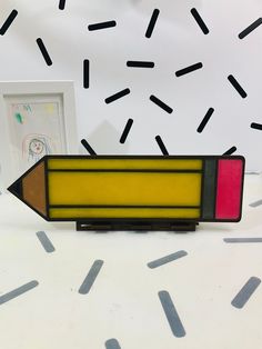 a pencil that is sitting on top of a table next to a framed photo and some confetti sprinkles