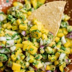 a wooden bowl filled with corn salsa and a tortilla chip