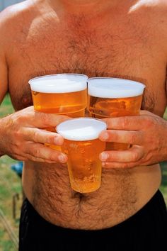 a man holding three glasses of beer in one hand and another with no shirt on