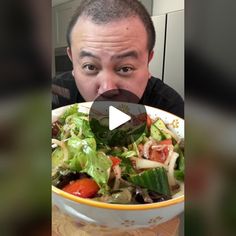 a man is making a funny face while holding a bowl of salad in front of his face