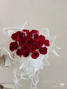 a bouquet of red roses is wrapped in clear cellophane and tied with ribbon