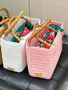 three baskets with handles are sitting on a black leather bench in front of a wall