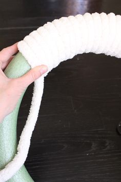 a hand is holding a white rope wrapped around a green object on a black table