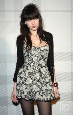 a young woman posing in front of a wall wearing tights and stockings with her hands on her hips