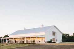 a large white barn sitting on top of a grass covered field