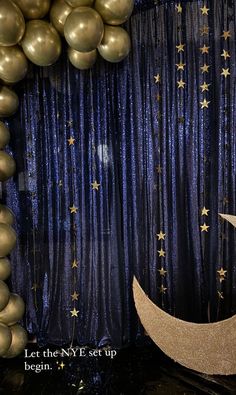 balloons and streamers are hanging from the ceiling in front of a blue curtain with gold stars