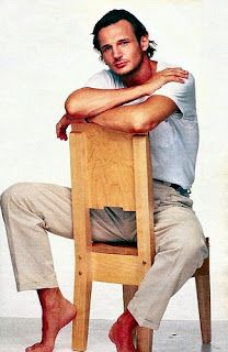 a man sitting on top of a wooden chair with his arms crossed and legs crossed