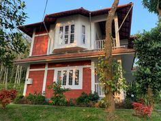 a red and white house sitting on top of a lush green hillside next to trees