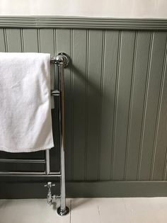 a towel rack with two white towels hanging on it's sides next to a green wall