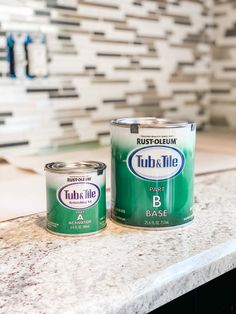 two cans of paint sitting on top of a counter