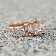 a three stone diamond ring sitting on top of a cement surface in front of the camera