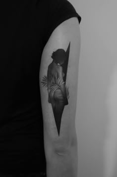 a black and white photo of a woman's arm with a tattoo on it