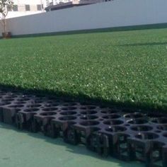 rows of black plastic drainage pipes in front of a white building with grass growing on the ground