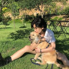 a woman sitting in the grass with her dog