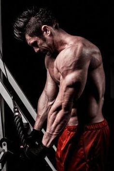 a man with no shirt on is holding a pair of boxing gloves