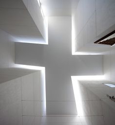 a cross is lit up in the middle of a room with white walls and flooring