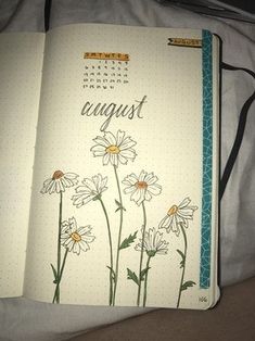 an open planner book with daisies and the word august written in cursive writing