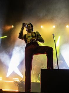 a man standing on top of a stage with his legs in the air while holding a microphone