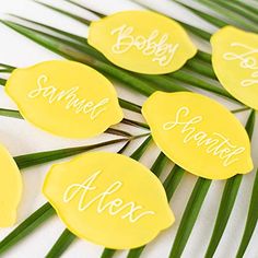 yellow palm leaves with names on them sitting on a white table cloth covered tablecloth