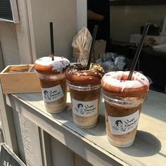 three desserts in plastic cups sitting on a window sill