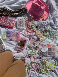 a person laying on top of a white blanket covered in beads and other items next to a pink hat