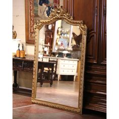 a large mirror sitting on top of a floor next to a wooden dresser and table