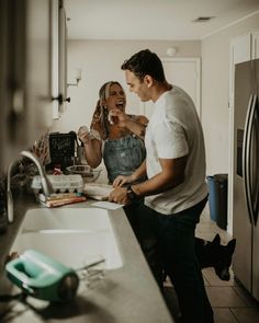 a man and woman standing in a kitchen next to a sink