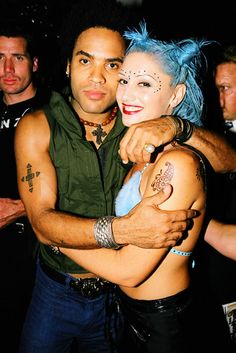 a man hugging a woman with blue hair and piercings on her face at a party