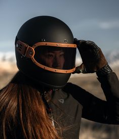 a woman wearing a motorcycle helmet and holding her hand up to her face